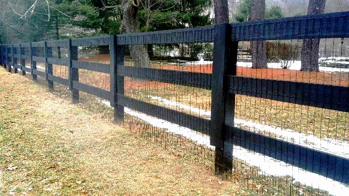 Black three-rail corral-style fence along a yard
