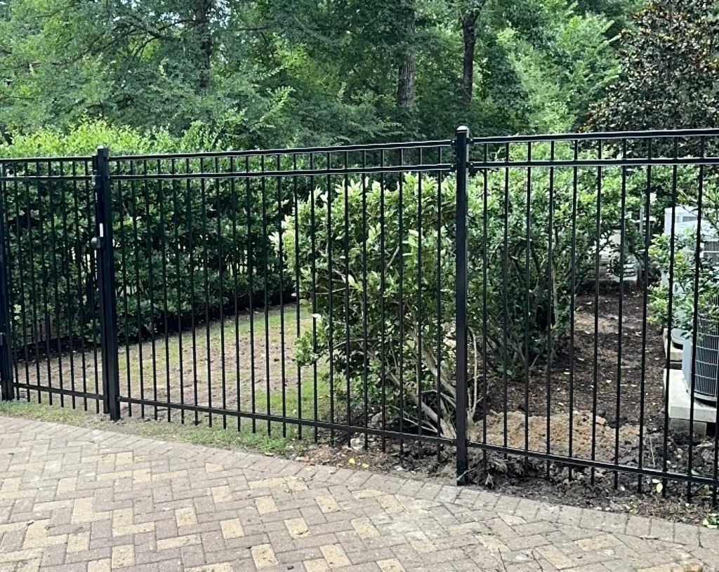 Black ornamental steel fence around a backyard patio